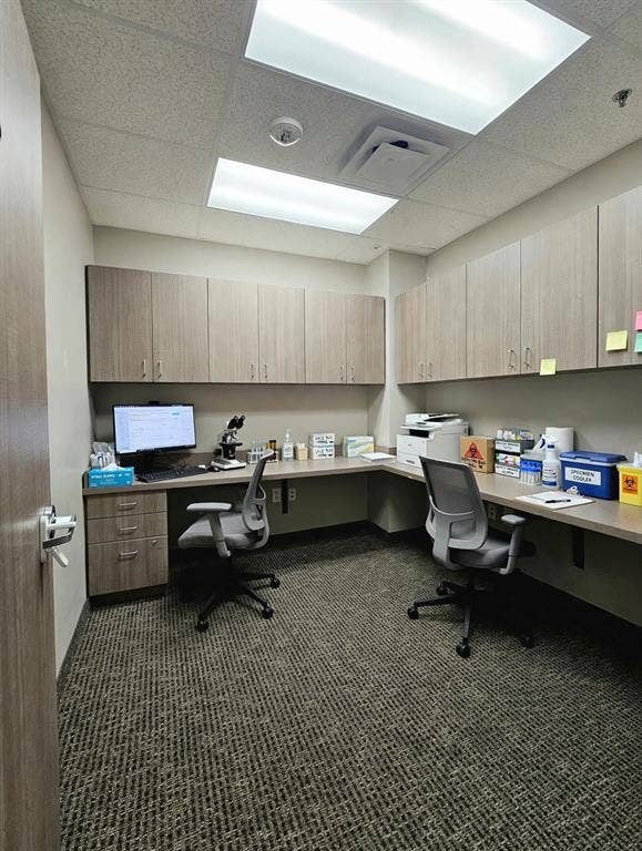 1675 Republic Parkway, #104, Mesquite, TX 75150 Corner office workspace featuring L-shaped countertop, under-cabinet storage, wood-finish cabinetry, and overhead fluorescent lighting