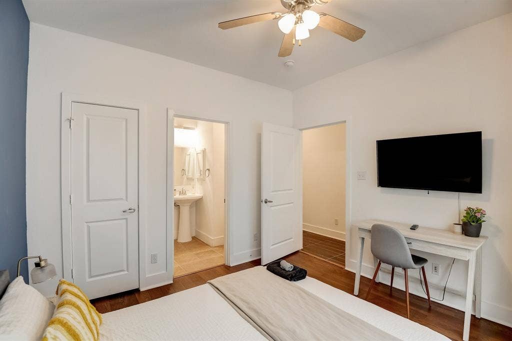 Bedroom with wood finished floors, baseboards, ceiling fan, and ensuite bathroom