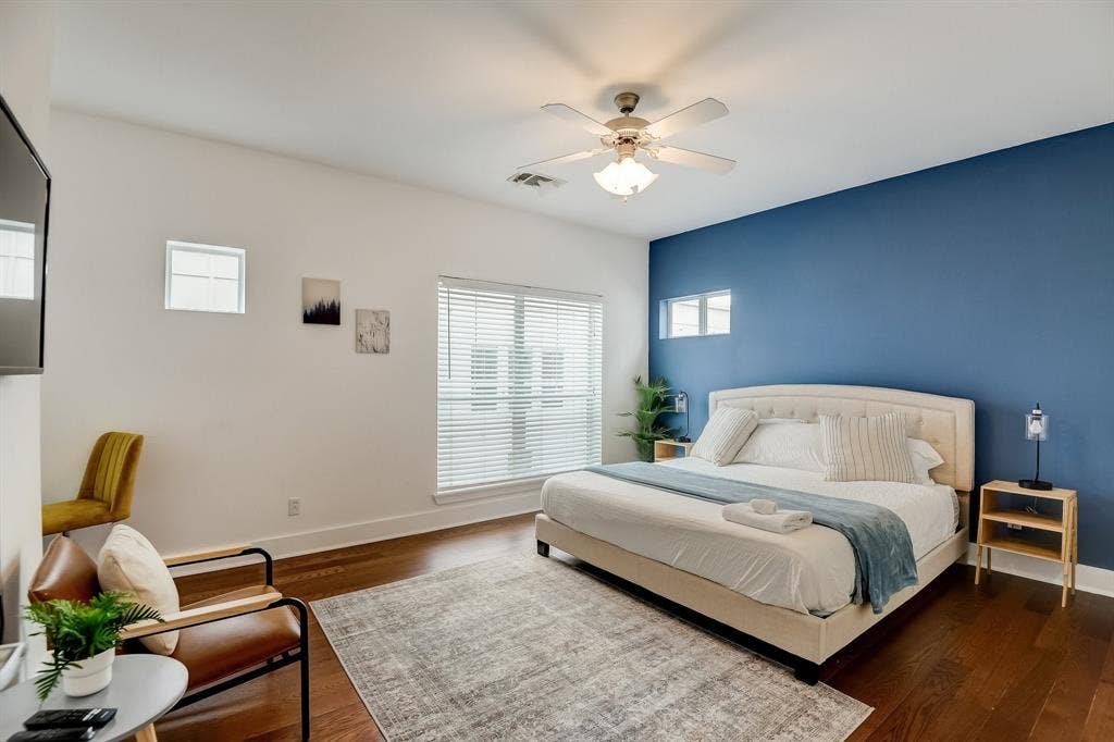 Bedroom with multiple windows, dark wood-type flooring, baseboards, and ceiling fan