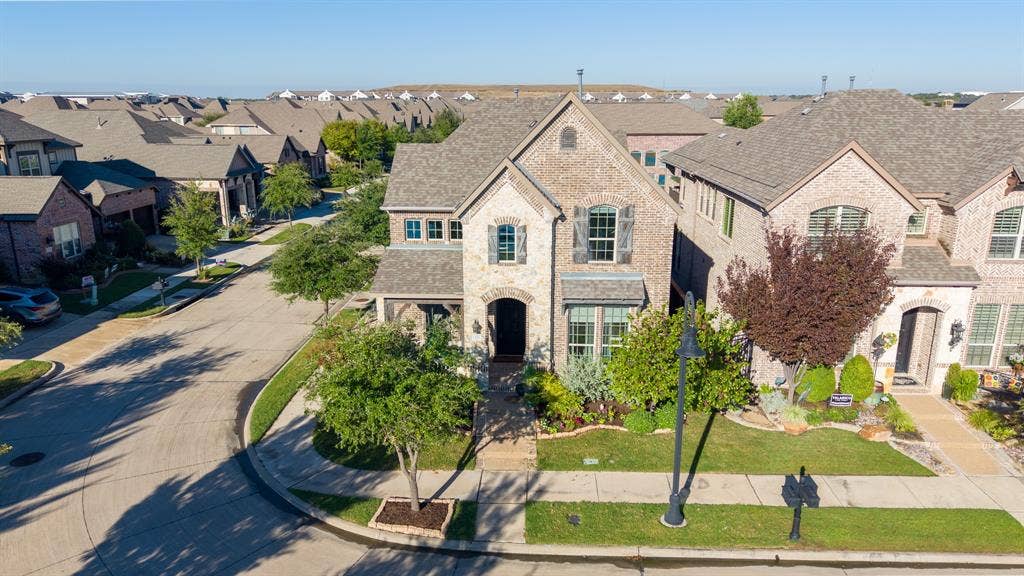 Brick and stone exterior featuring multiple gables, arched entryways, and mature landscaping