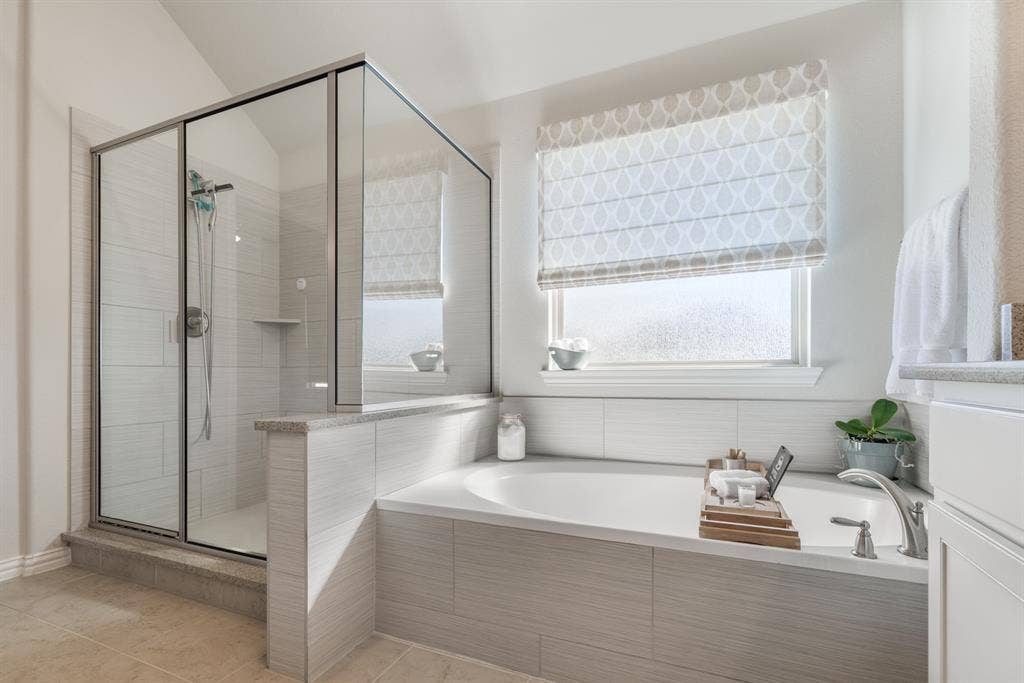 Built-in soaking tub with deck-mounted faucet, tile surround, and adjacent glass-enclosed shower with tiled walls and built-in shelf