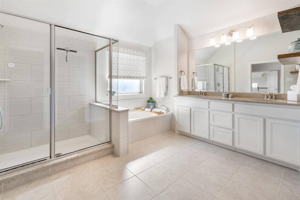Spacious bathroom with a glass-enclosed shower, built-in soaking tub, dual vanity with undermount sinks, and light-toned tile flooring