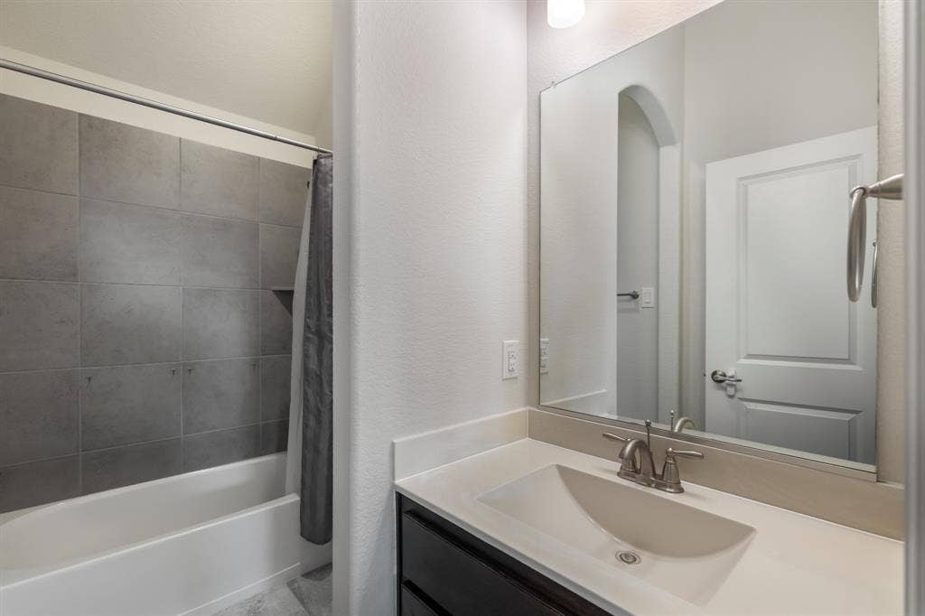 Upstairs jack and jill bathroom with tub and shower combination with grey tile surround and built-in niche