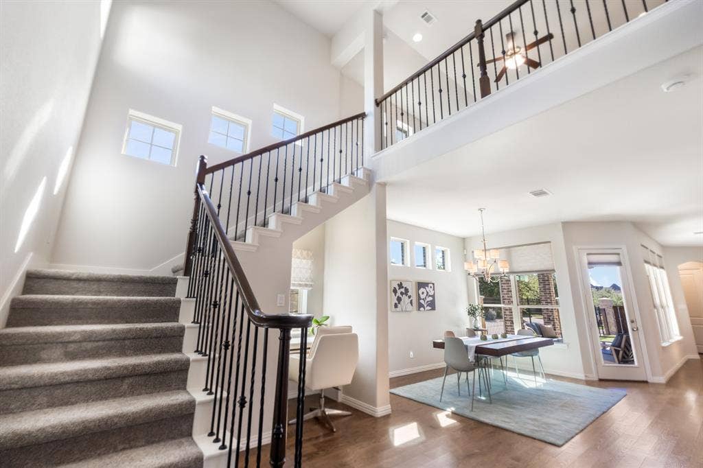 Two-story foyer with a carpeted staircase, wrought iron balusters, and a wood handrail