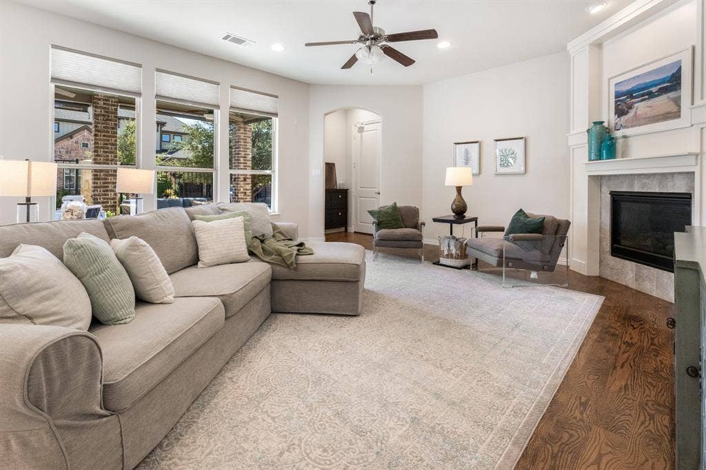 Wood-finish flooring with a fireplace featuring a tiled surround and mantel