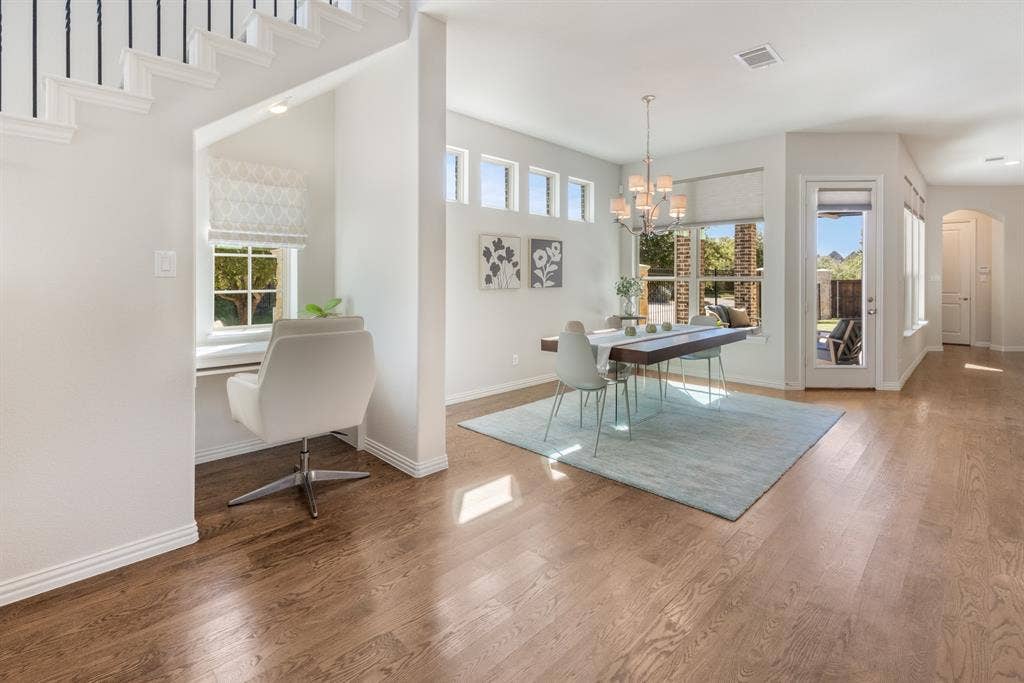 Built-in desk area with a window, wood-finish flooring, dining area with chandelier, large windows, and a glass-paneled door