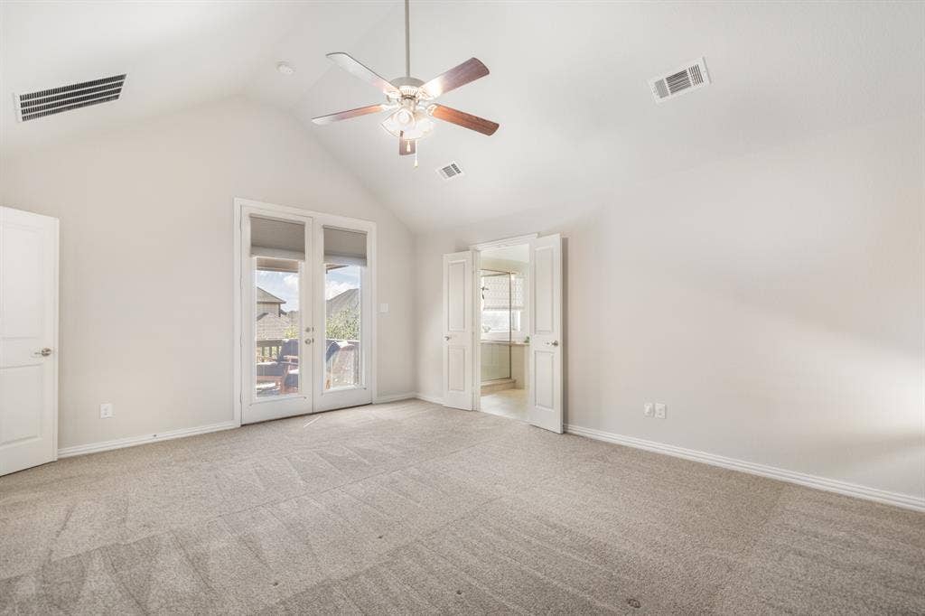 Vaulted ceiling with a ceiling fan, carpet flooring, double doors with exterior access, and additional interior door access