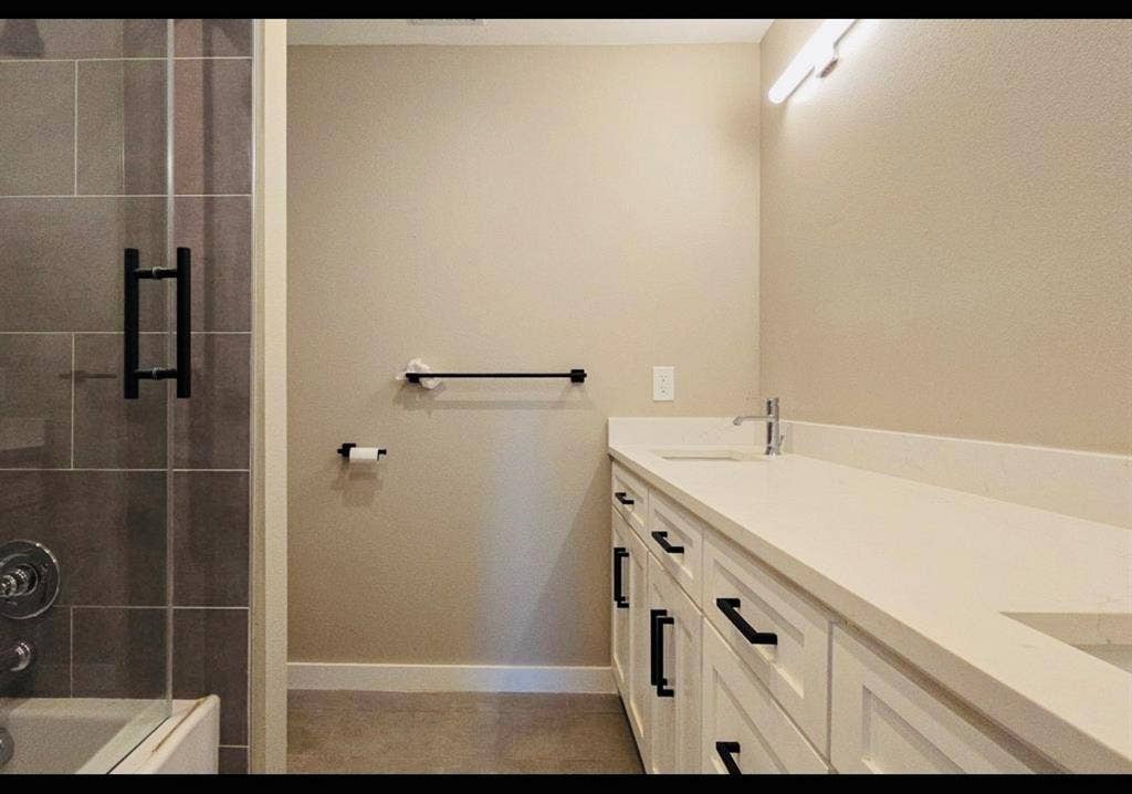2821 Avenue L, Fort Worth, TX 76105 Dual vanity with white cabinetry, matte black hardware, and a light-toned countertop