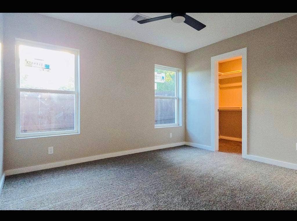 2821 Avenue L, Fort Worth, TX 76105 Gray carpeting with light-toned walls, two windows, and a ceiling fan