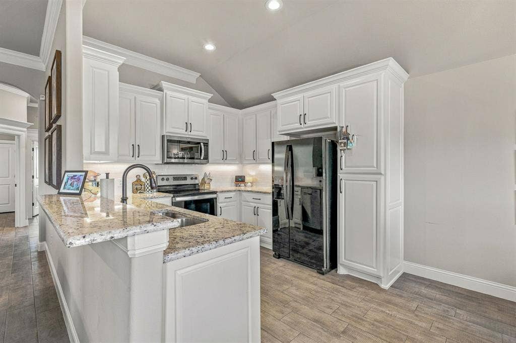 601 Violet Drive, Tolar, TX 76476 White cabinetry with crown molding details, light-toned granite countertops, stainless steel appliances, wood-finish flooring, and recessed lighting