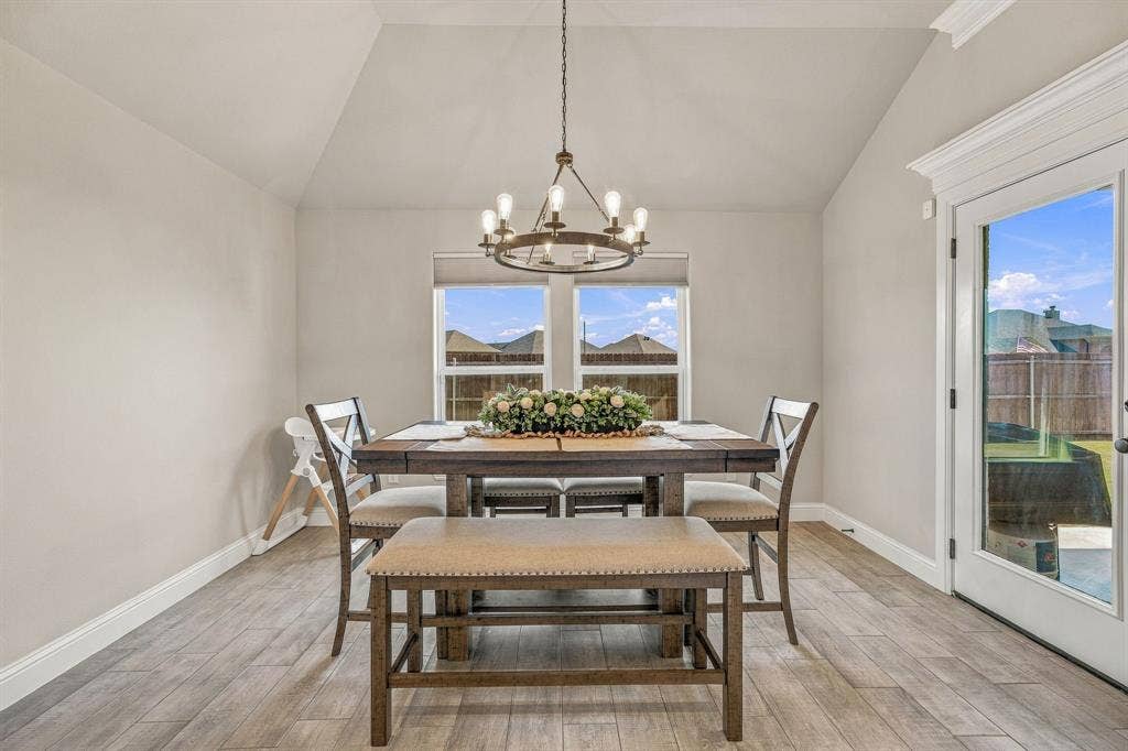 601 Violet Drive, Tolar, TX 76476 Vaulted ceilings with a chandelier, wood-finish flooring, two windows with roller shades, and a glass-paneled door