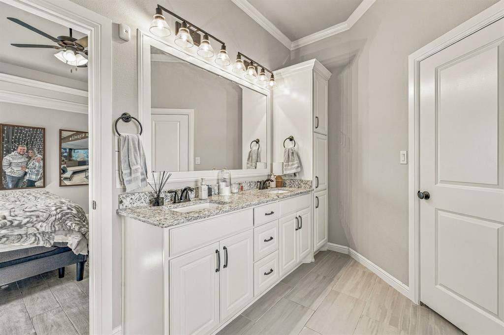 601 Violet Drive, Tolar, TX 76476 Dual vanity with granite countertop and undermount sinks, flanked by white cabinetry and a built-in tall linen cabinet