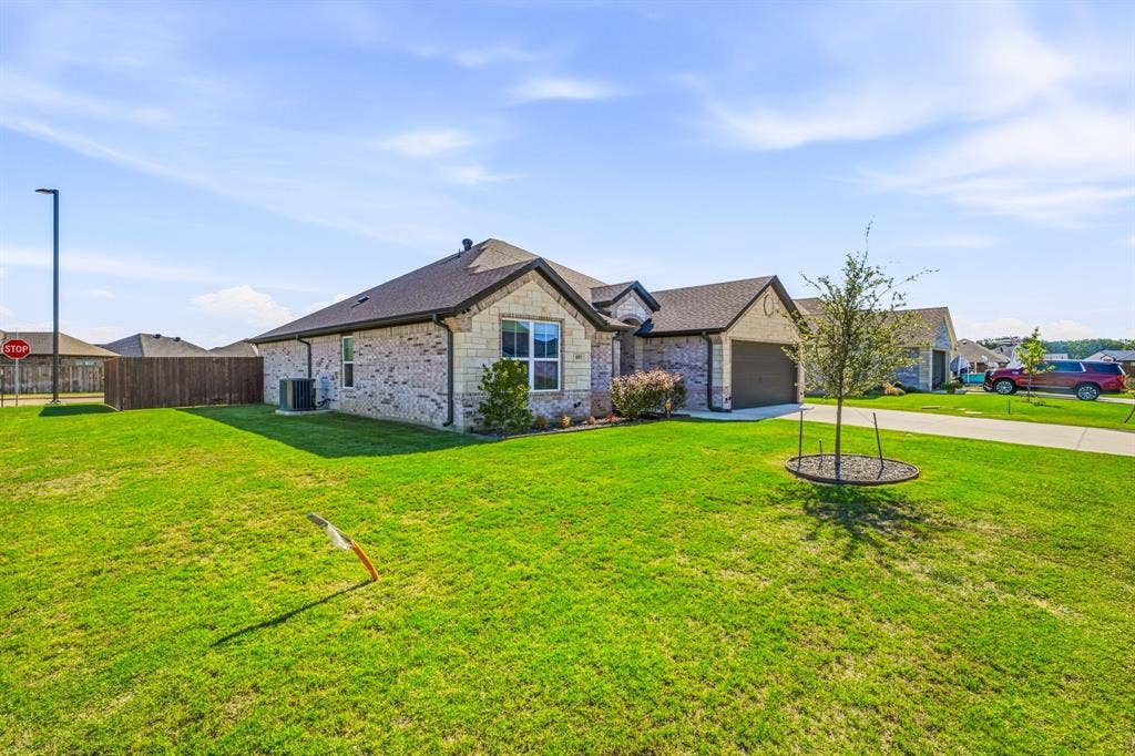 601 Violet Drive, Tolar, TX 76476 Brick and stone exterior, attached garage, concrete driveway, fenced perimeter, and landscaped yard