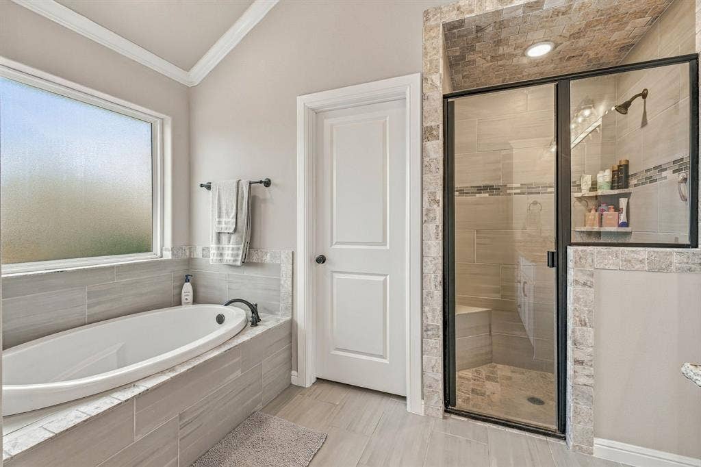 601 Violet Drive, Tolar, TX 76476 Soaking tub with a dark bronze faucet, walk-in shower with glass enclosure, tiled shower bench, and a vaulted ceiling