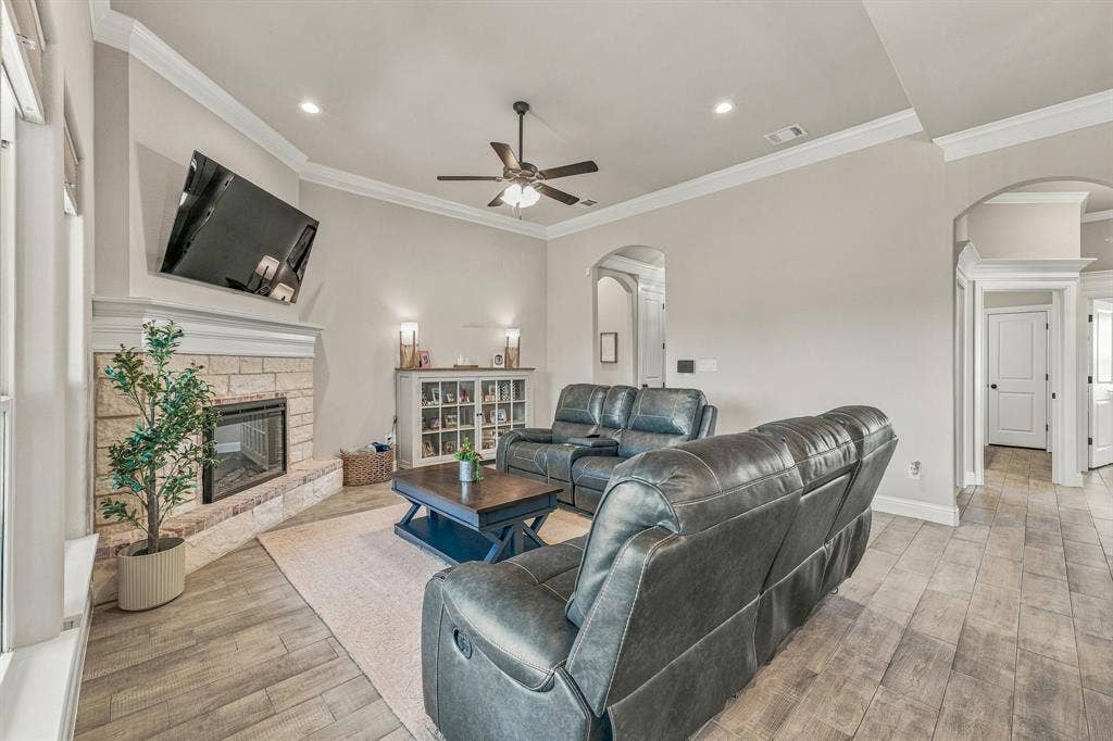 601 Violet Drive, Tolar, TX 76476 Living area featuring a stone-clad fireplace with a hearth, wood-finish flooring, vaulted ceiling with a fan, recessed lighting, and arched doorways
