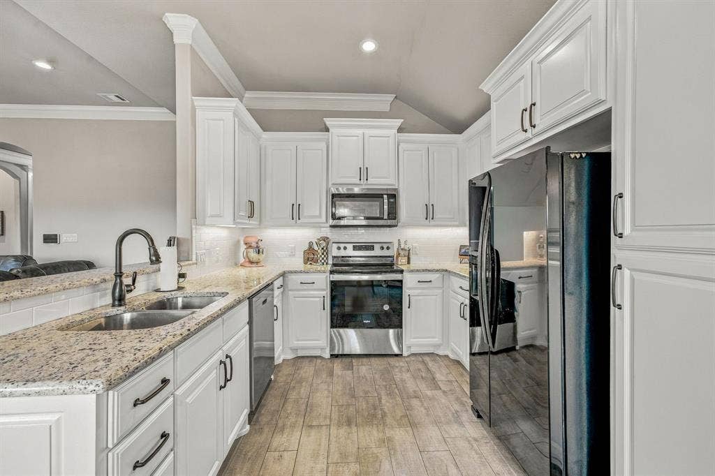 601 Violet Drive, Tolar, TX 76476 Kitchen featuring extensive white cabinetry, granite countertops, subway tile backsplash, stainless steel appliances, and wood-finish flooring