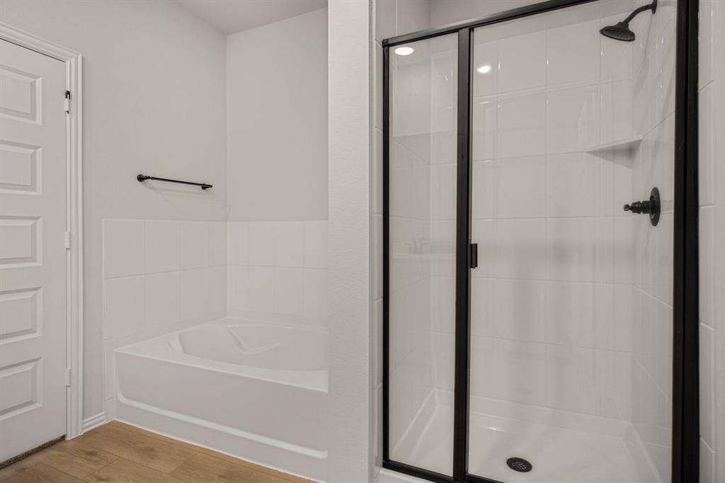 3517 Foxhound Lane, Denton, TX 76208 Walk-in shower with clear glass enclosure and matte black fixtures, white tiled walls, and a corner bathtub