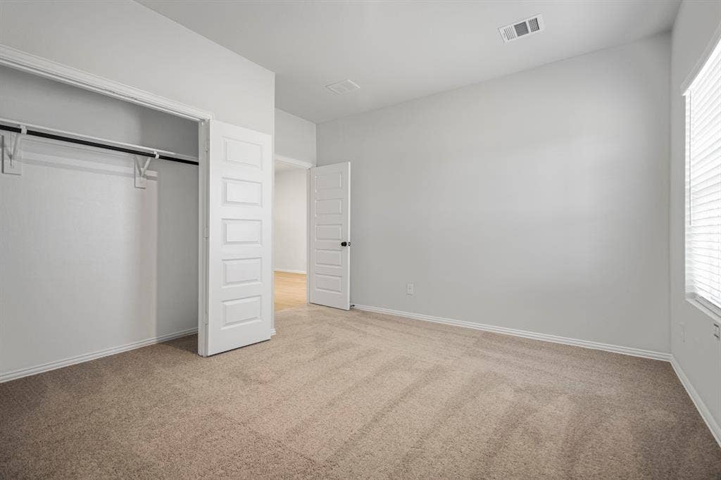 3517 Foxhound Lane, Denton, TX 76208 Neutral wall color, wall-to-wall carpeting, window with blinds, and a built-in closet with hanging rod