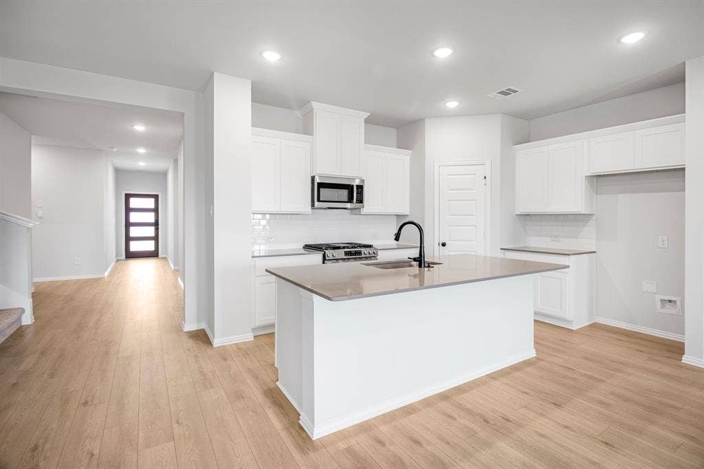 3517 Foxhound Lane, Denton, TX 76208 Kitchen featuring white cabinetry, a central island with a sink, stainless steel appliances, and wood-finish flooring