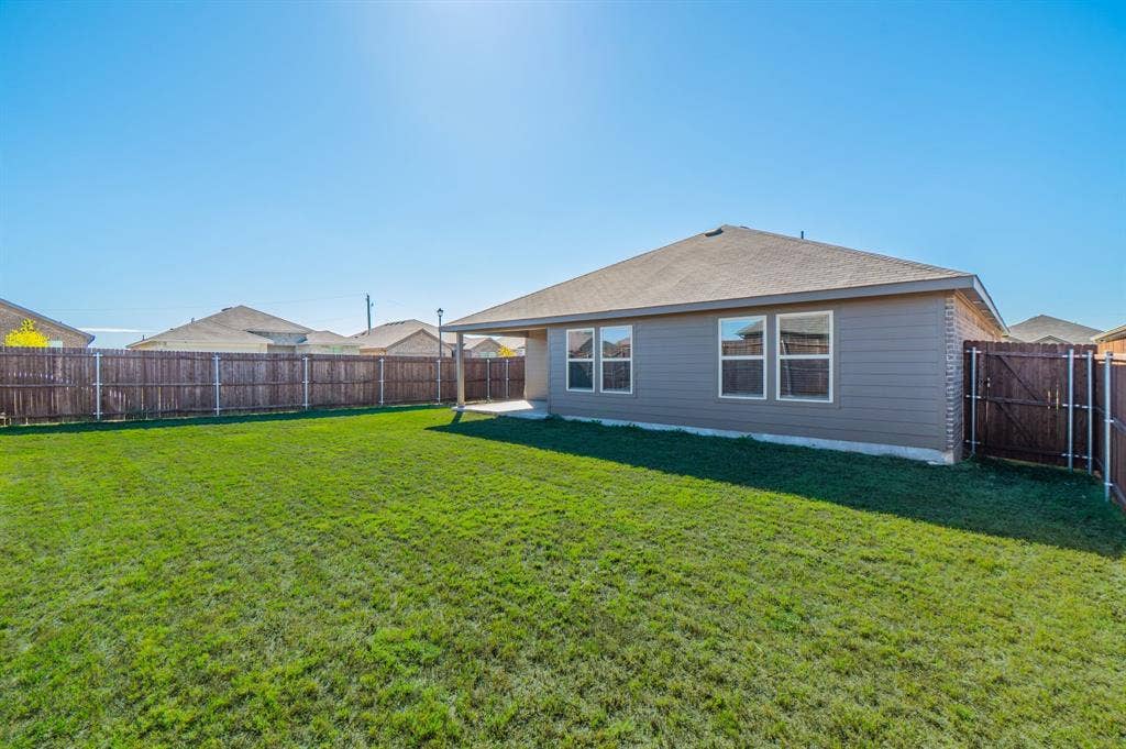 1842 Shady Elm Drive, Lancaster, TX 75146 Expansive green lawn, wood fence, concrete patio, and exterior siding