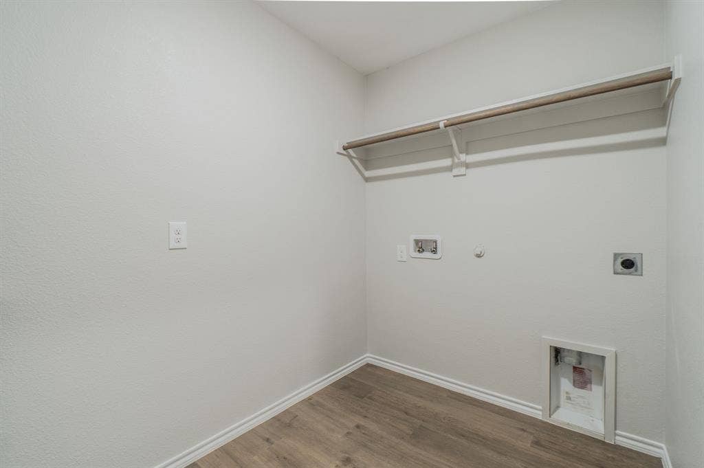 1842 Shady Elm Drive, Lancaster, TX 75146 Laundry area featuring wood-finish flooring, a wall-mounted shelving unit with a hanging rod, and utility hookups