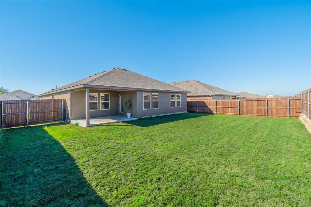 1842 Shady Elm Drive, Lancaster, TX 75146 Expansive backyard featuring a manicured lawn, full privacy fencing, and a covered patio area