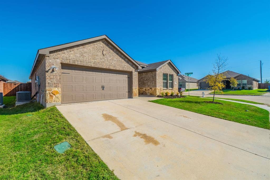 1842 Shady Elm Drive, Lancaster, TX 75146 Brick exterior with stone accents, attached two-car garage, concrete driveway, and front lawn