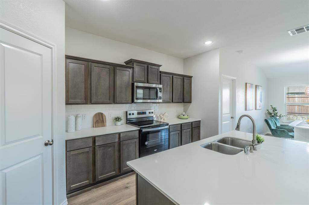 1842 Shady Elm Drive, Lancaster, TX 75146 Kitchen featuring dark wood-finish cabinetry, white subway tile backsplash, white countertops, and stainless steel appliances