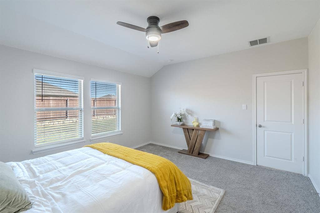 1842 Shady Elm Drive, Lancaster, TX 75146 Vaulted ceiling with a contemporary ceiling fan, two double-hung windows with blinds, light gray wall paint, and gray carpeting