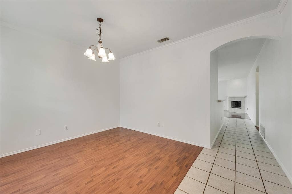 Wood-finish flooring, overhead chandelier, white wall finishes, crown molding, and tiled flooring