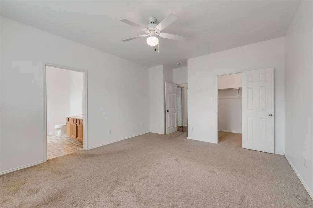 Carpeted flooring, ceiling fan with integrated lighting, white interior doors, and a built-in closet with shelving