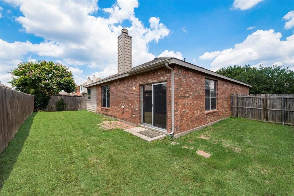 Brick exterior featuring a tall chimney, multiple windows, and a sliding glass door