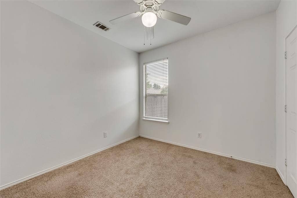 Carpeted room featuring a ceiling fan with integrated lighting, a window with blinds, and white walls