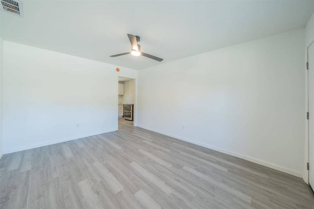 Light wood-finish flooring with a modern ceiling fan and recessed lighting
