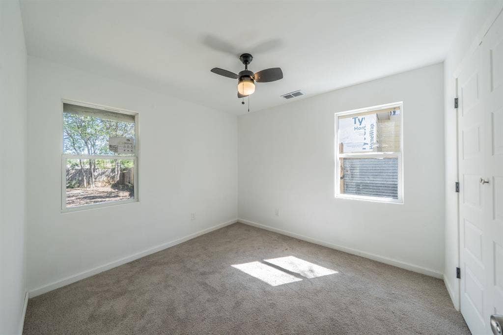 Plush carpeting, neutral wall finish, and a ceiling fan with integrated lighting