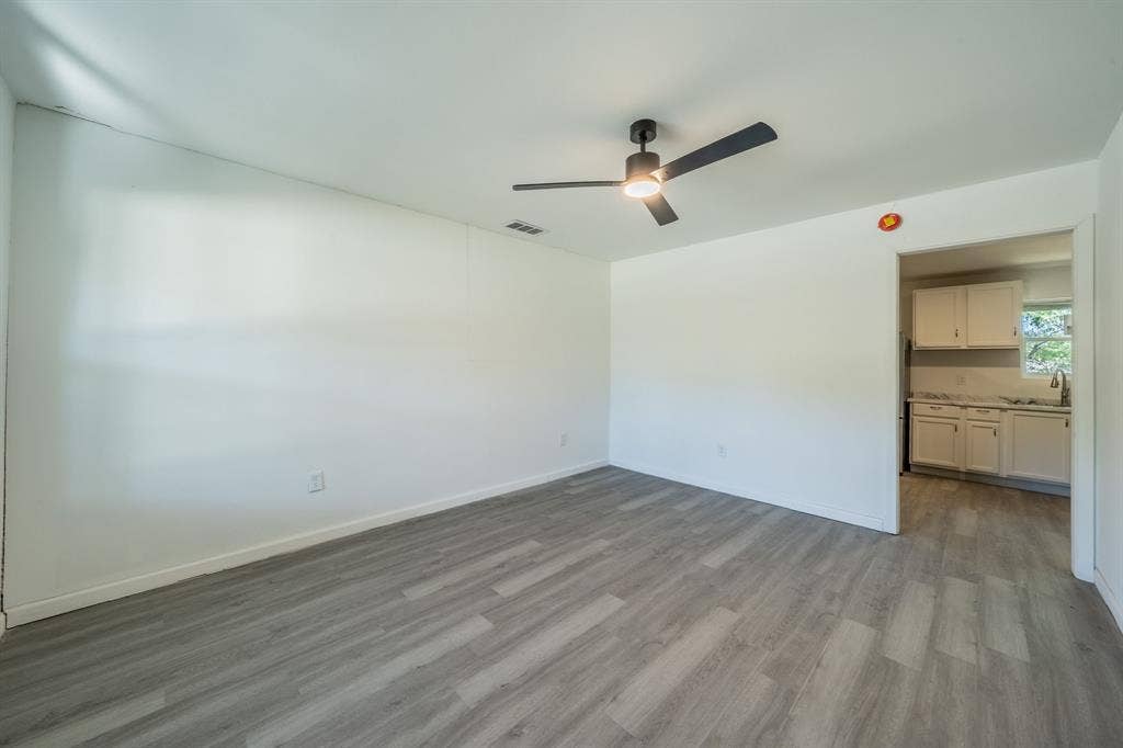 Wood-finish plank flooring, ceiling fan with integrated lighting, and white painted walls