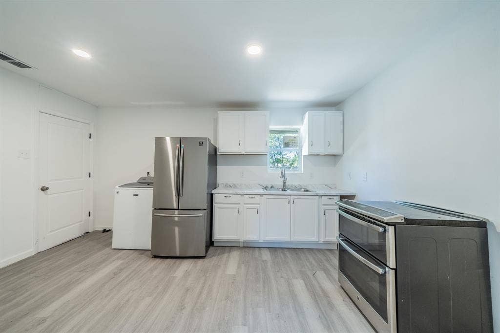 White cabinetry with brushed nickel hardware, stainless steel appliances, wood-finish flooring, and recessed lighting