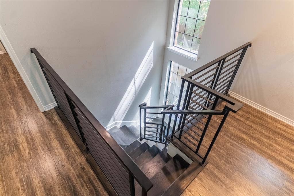 Staircase featuring dark wood-finish treads and risers, black metal railings, and wood-finish flooring