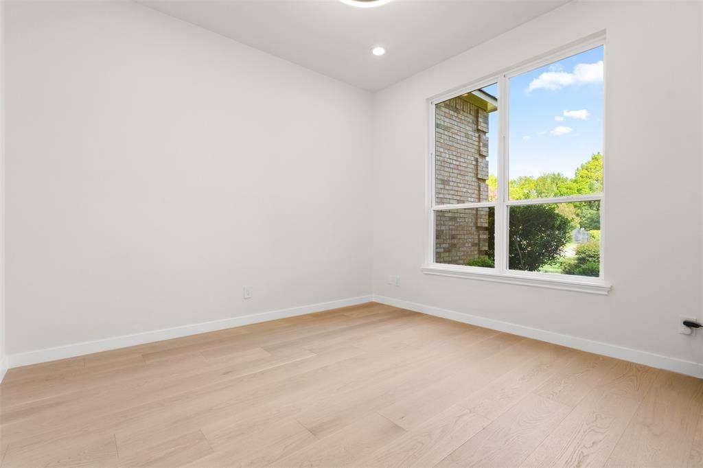 Light wood-finish flooring, recessed lighting, and a large window with white trim