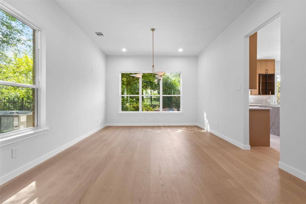 Open-concept room with light wood-finish flooring, recessed lighting, and a modern pendant light fixture