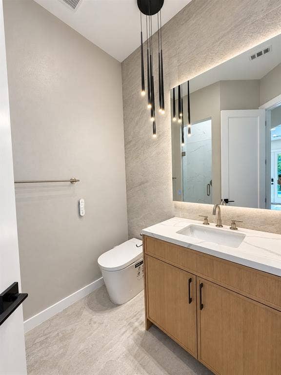 Modern vanity with a white countertop and integrated sink, brushed nickel faucet, wood-finish cabinetry, and black hardware
