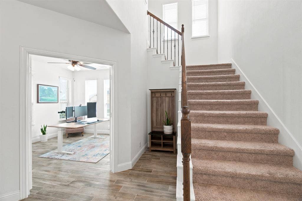 1218 Misty Ridge Drive, Justin, TX 76247 Staircase with carpeted treads and wood handrail, featuring wrought iron balusters