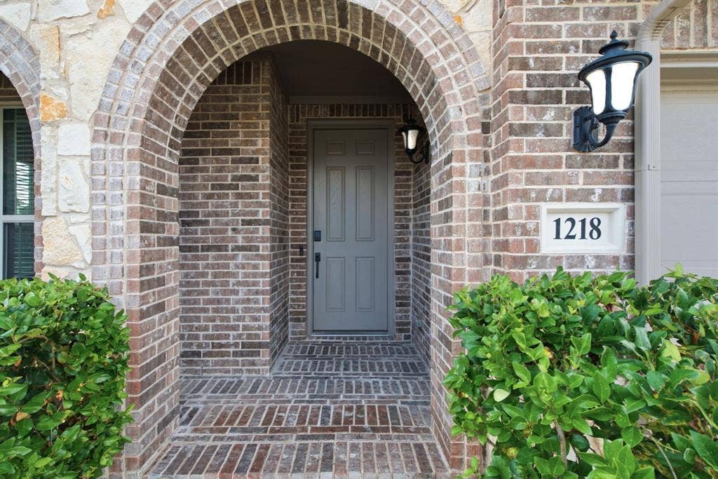 1218 Misty Ridge Drive, Justin, TX 76247 Brick and stone veneer exterior featuring an arched entryway and brick flooring