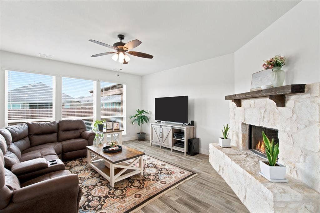 1218 Misty Ridge Drive, Justin, TX 76247 Living area featuring a stone-clad fireplace with a wood mantel, wood-look tile flooring, and multiple windows