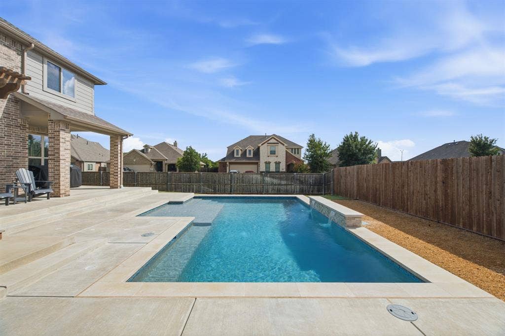 1218 Misty Ridge Drive, Justin, TX 76247 Backyard featuring a rectangular swimming pool, concrete patio, covered patio with brick columns, and a wood privacy fence