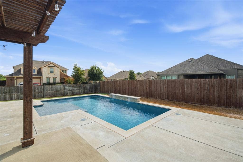 1218 Misty Ridge Drive, Justin, TX 76247 Outdoor swimming pool with freestanding spa feature, surrounding concrete decking, wood pergola, and privacy fencing