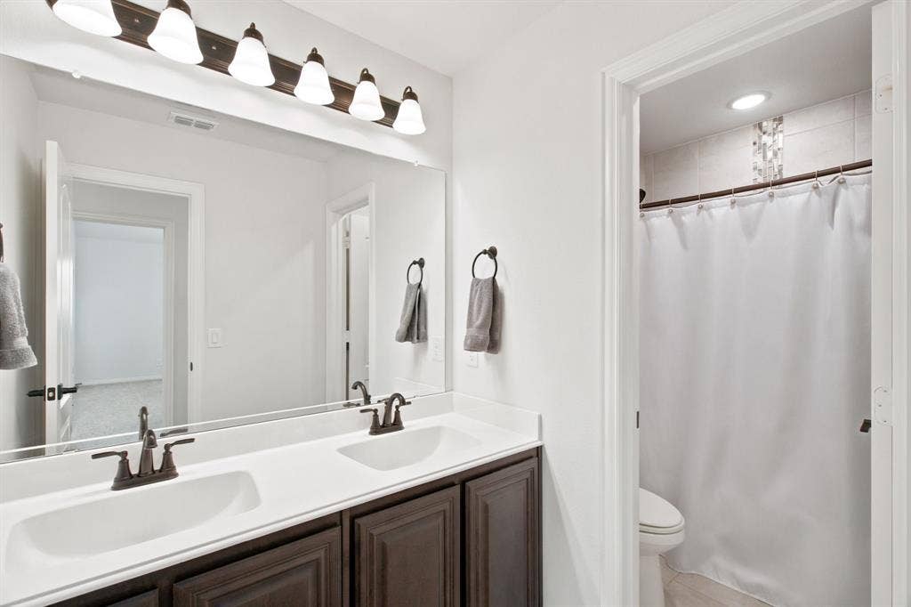 1218 Misty Ridge Drive, Justin, TX 76247 Dual vanity with integrated sinks, dark wood-finish cabinetry, and oil-rubbed bronze fixtures
