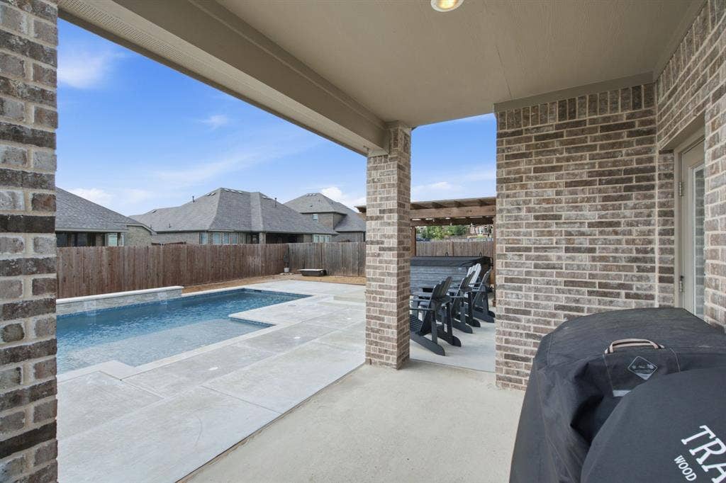 1218 Misty Ridge Drive, Justin, TX 76247 Covered patio area with brick exterior walls, recessed lighting, and an adjacent swimming pool with integrated steps