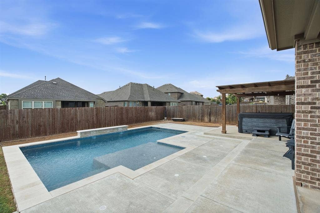 1218 Misty Ridge Drive, Justin, TX 76247 Expansive concrete patio with a rectangular swimming pool, freestanding spa, wood pergola, and brick exterior