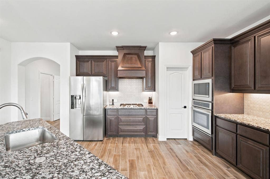 1218 Misty Ridge Drive, Justin, TX 76247 Kitchen featuring wood-look tile flooring, dark wood cabinetry, and speckled countertops